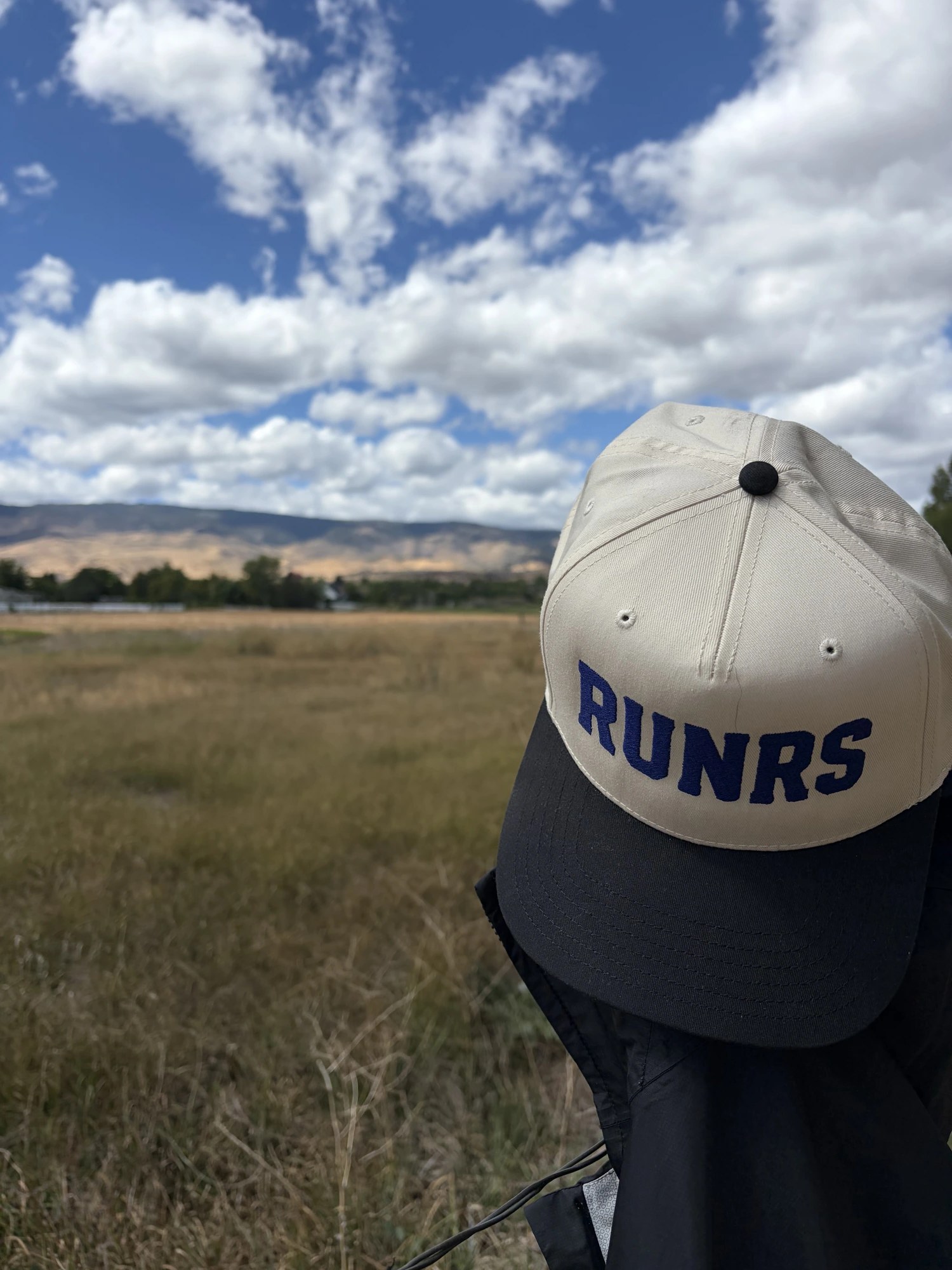 RUNRS cap on the trail, mountains behind